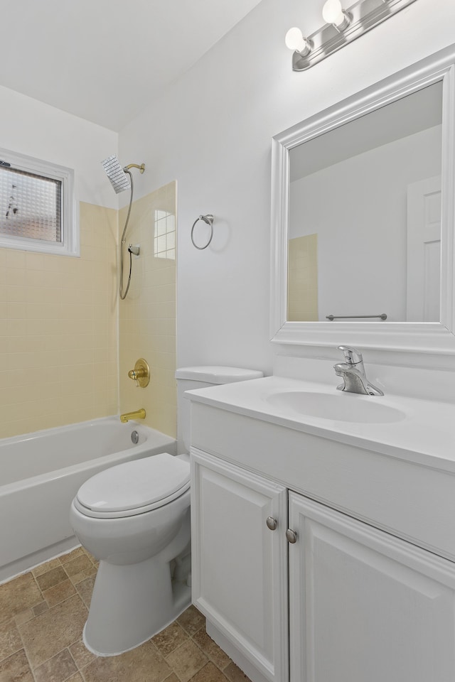 bathroom featuring stone finish flooring, toilet, shower / bathtub combination, and vanity