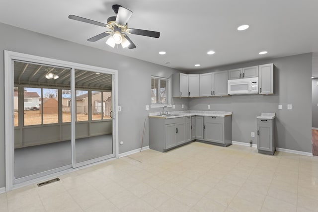 kitchen featuring recessed lighting, visible vents, white microwave, and gray cabinetry