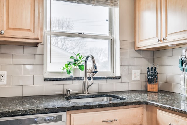 kitchen featuring sink, dishwashing machine, backsplash, dark stone counters, and light brown cabinets