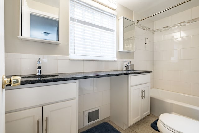 full bathroom featuring tiled shower / bath, tile walls, vanity, toilet, and tile patterned floors