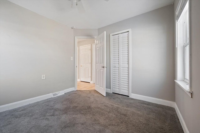 unfurnished bedroom with carpet, ceiling fan, and a closet