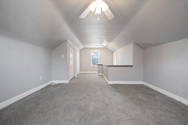 bonus room featuring lofted ceiling, ceiling fan, a textured ceiling, and carpet