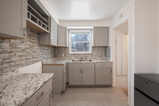 kitchen with gray cabinets, sink, light stone countertops, and backsplash