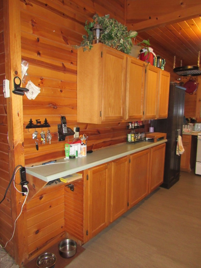 kitchen with light wood-type flooring, wood ceiling, and black fridge