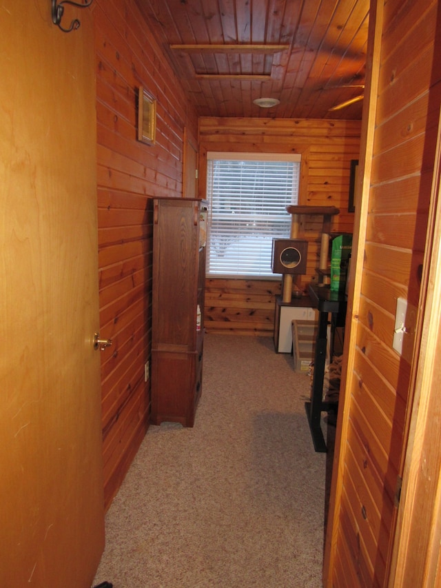 hallway with light colored carpet, wood walls, and wood ceiling