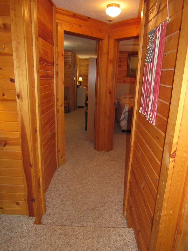 hall with light carpet and wooden walls