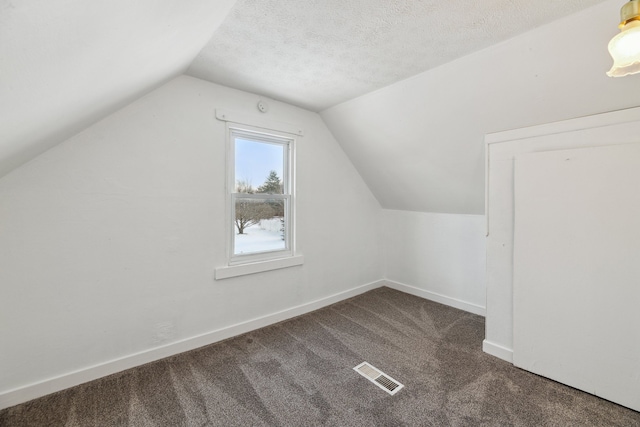 bonus room with lofted ceiling, a textured ceiling, and dark colored carpet