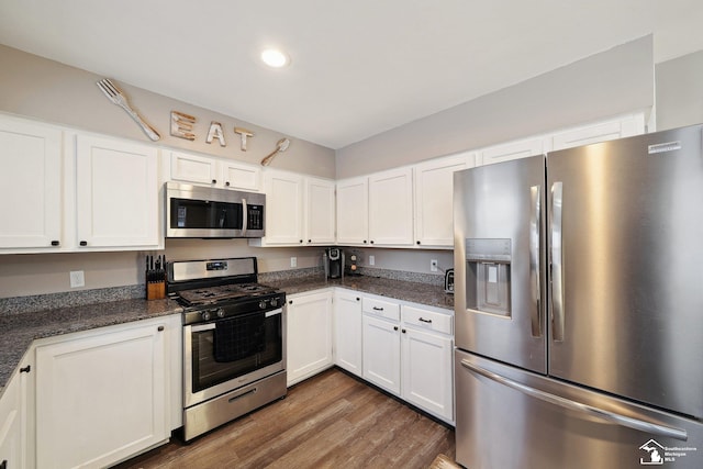 kitchen with white cabinets, dark wood-type flooring, dark stone countertops, and stainless steel appliances