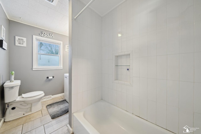 bathroom featuring toilet, tiled shower / bath, and tile patterned flooring