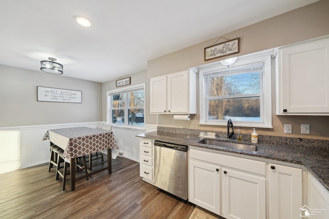 kitchen featuring sink, white cabinetry, stainless steel dishwasher, and dark stone countertops