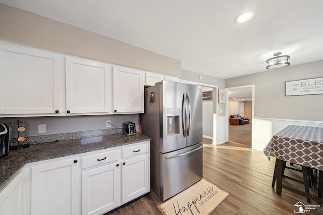 kitchen featuring white cabinets, stainless steel refrigerator with ice dispenser, dark stone counters, and dark hardwood / wood-style flooring