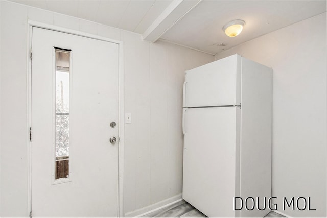 interior space featuring white refrigerator and beam ceiling