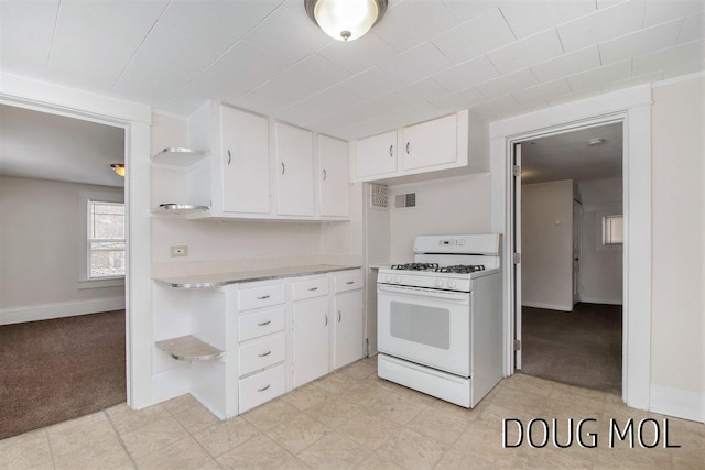 kitchen featuring white cabinetry, gas range gas stove, and light carpet