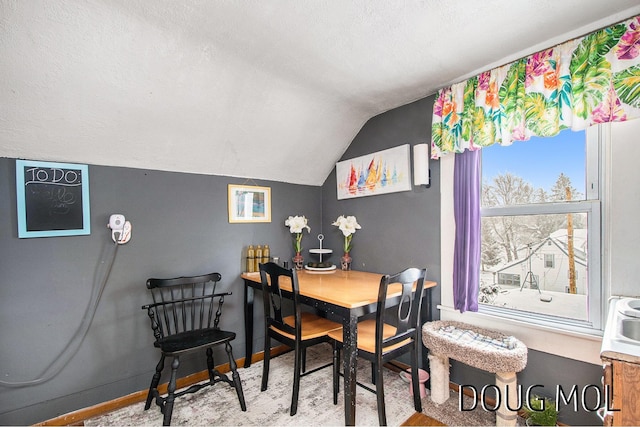 carpeted dining space with vaulted ceiling