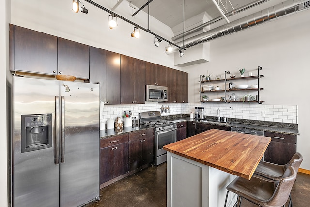 kitchen featuring wooden counters, sink, backsplash, a breakfast bar, and stainless steel appliances