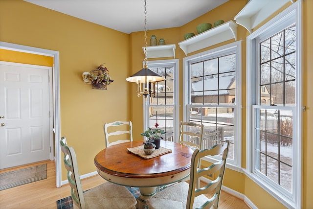 dining space with light hardwood / wood-style flooring, an inviting chandelier, and a healthy amount of sunlight