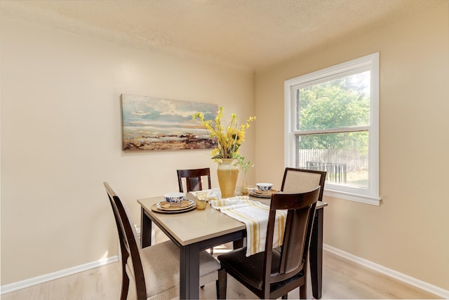 dining room featuring light wood-type flooring and a textured ceiling