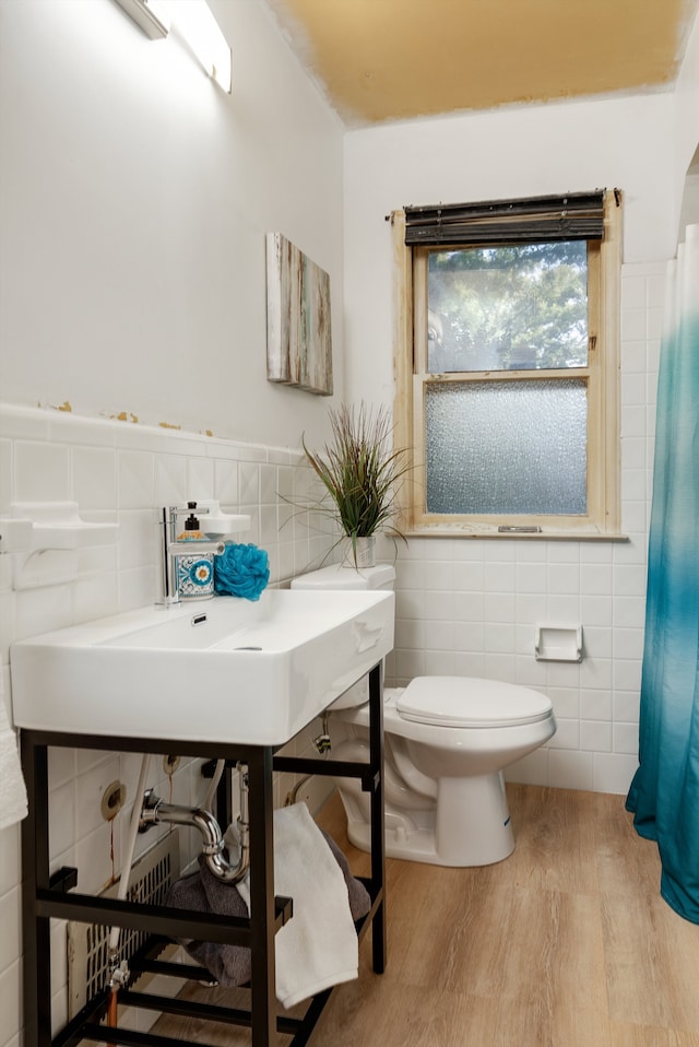 bathroom with hardwood / wood-style flooring, toilet, and tile walls