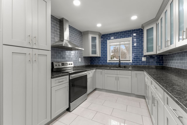 kitchen featuring stainless steel range with electric cooktop, wall chimney range hood, sink, backsplash, and gray cabinetry