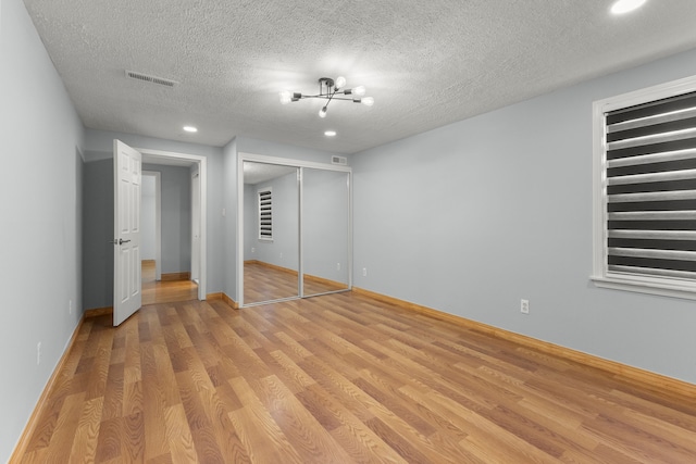 unfurnished bedroom with a closet, light hardwood / wood-style flooring, and a textured ceiling