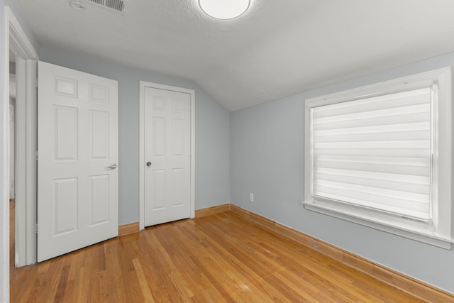 additional living space featuring light hardwood / wood-style flooring, a textured ceiling, and lofted ceiling