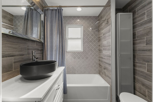 full bathroom with shower / bath combo with shower curtain, tile walls, toilet, and vanity