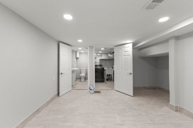 basement with sink, washer / clothes dryer, and light tile patterned floors