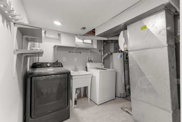 clothes washing area featuring water heater, heating unit, and washing machine and clothes dryer