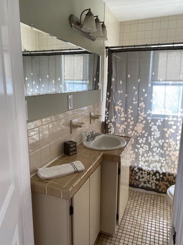 bathroom with toilet, vanity, tile patterned floors, and tile walls