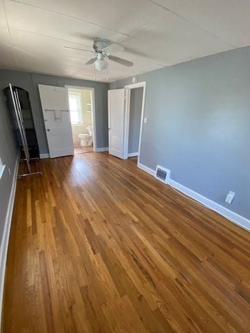 unfurnished bedroom with hardwood / wood-style flooring, ensuite bathroom, and ceiling fan