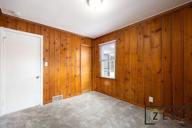 empty room featuring wooden walls and carpet