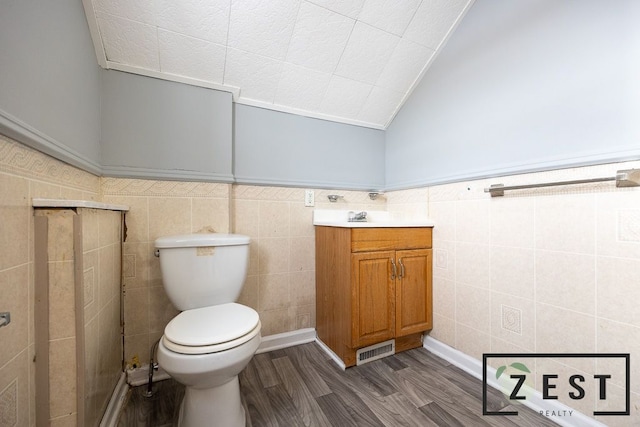 bathroom featuring lofted ceiling, hardwood / wood-style flooring, tile walls, and toilet