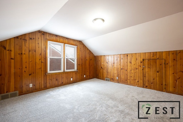 additional living space with lofted ceiling, wooden walls, and carpet floors