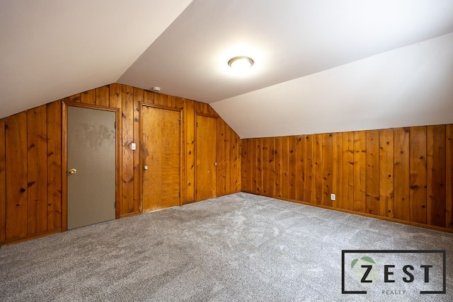 additional living space with carpet flooring, wooden walls, and vaulted ceiling