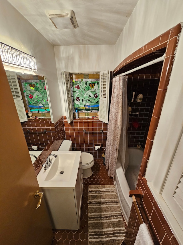 full bathroom with tile patterned floors, vanity, shower / bath combination with curtain, tile walls, and toilet