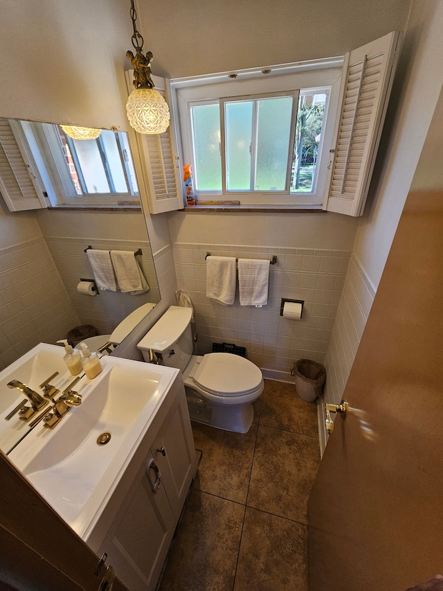 bathroom with toilet, vanity, tile patterned floors, and tile walls