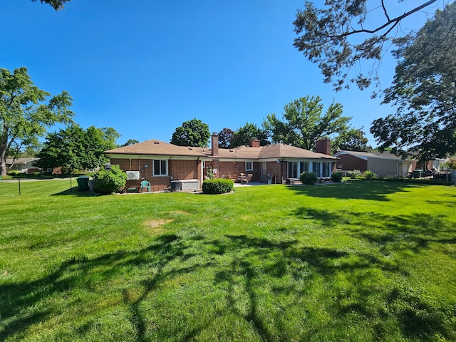 back of house featuring central air condition unit and a lawn