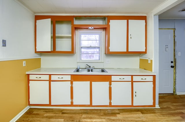 kitchen featuring light hardwood / wood-style floors, sink, white cabinetry, and ornamental molding