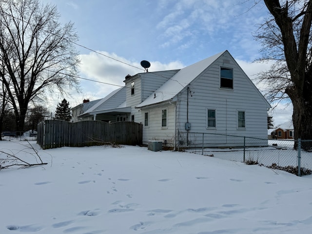 snow covered back of property featuring central air condition unit