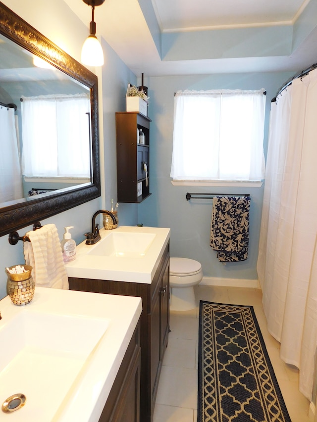 bathroom featuring tile patterned floors, vanity, a raised ceiling, and toilet