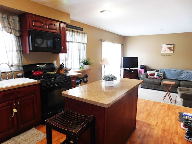 kitchen featuring black appliances, a kitchen island, light hardwood / wood-style flooring, and sink