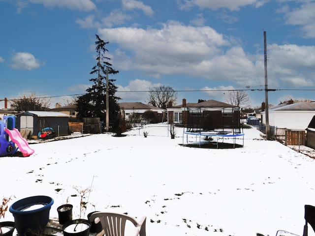 yard covered in snow with a playground and a trampoline