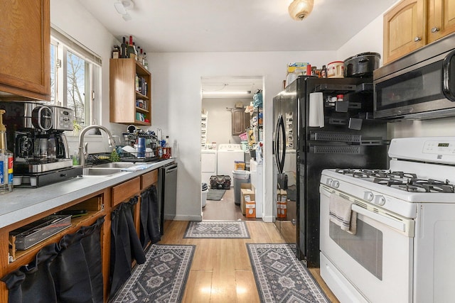 kitchen featuring washer and clothes dryer, white range with gas stovetop, sink, and light hardwood / wood-style floors