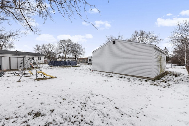 yard layered in snow with a shed and a pool