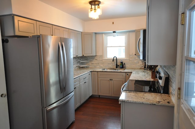 kitchen featuring backsplash, sink, dark wood-type flooring, appliances with stainless steel finishes, and light stone counters