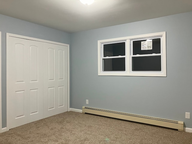 unfurnished bedroom with a closet, carpet, and baseboard heating