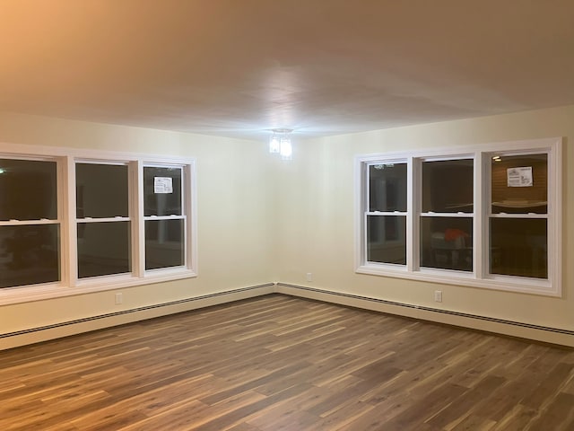 unfurnished room with baseboard heating and dark wood-type flooring