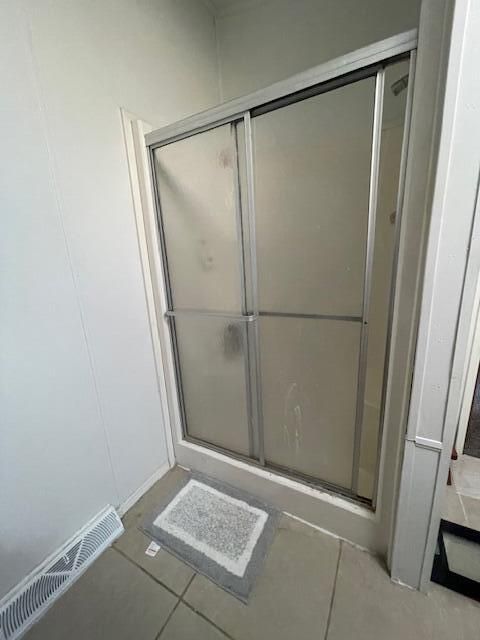 bathroom featuring a shower with shower door and tile patterned flooring