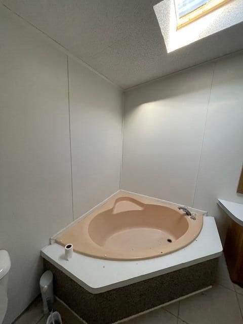 bathroom with tile patterned floors, toilet, a skylight, and a textured ceiling