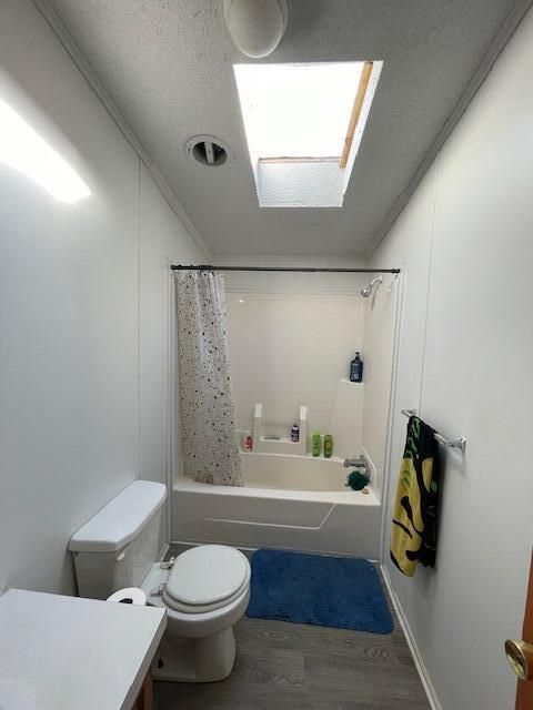 full bathroom featuring hardwood / wood-style flooring, toilet, vanity, ornamental molding, and shower / bathtub combination with curtain